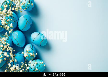 Dyed Easter eggs with flowers on pastel blue background. Top view. Flat lay. Stock Photo