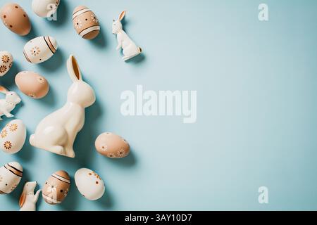 Easter eggs decorated with flowers, decorative Easter rabbits on pastel blue background. Top view. Flat lay. Stock Photo