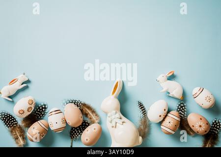 Easter background with natural floral painted eggs, feathers, rabbits on pastel blue table. Flat lay. Top view. Stock Photo
