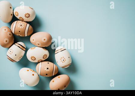 Floral painted eggs in natural colors on pastel blue background. Happy Easter concept. Stock Photo