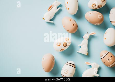 Happy Easter card. Flat lay composition with brown and white Easter eggs and Easter rabbits on pastel blue background. Stock Photo