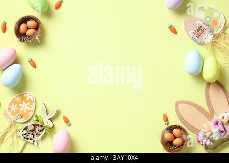 Happy Easter card. Flat lay composition with bunny ears decorated flowers, nests of eggs, wooden decorations, colorful Easter eggs on light green back Stock Photo