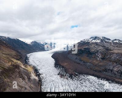 Aerial view of Vatnajökull glacier flowing through a steep valley surrounded by Icelandic mountains. Stock Photo