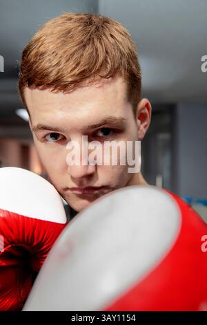 Portrait of a determined young boxer wearing boxing gloves, posing in a boxing gym, ready for training or competition Stock Photo