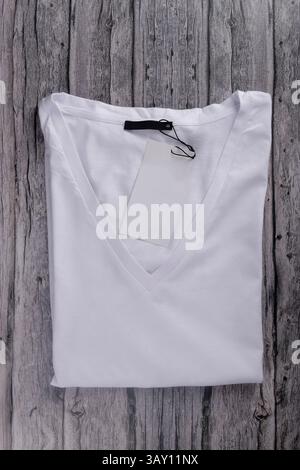 flat law of white V-neck t-shirt folded with label on vintage gray wood Stock Photo