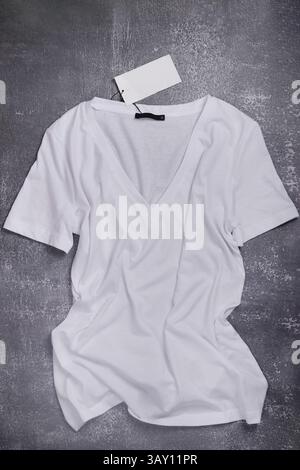 top view of white V-neck t-shirt with label on rustic background Stock Photo