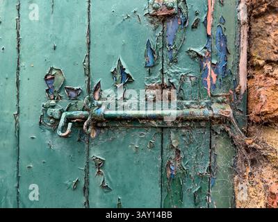 Old bolt lock with on a wooden door with peeling green paint Stock Photo