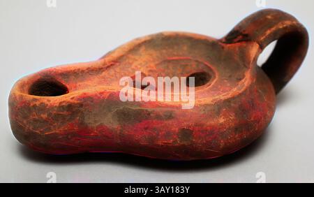 An ancient oil lamp featuring a unique, organic shape and ornate designs, displaying two circular openings for wicks and a handle for easy use. The surface shows signs of age, adding character to this historical artifact., Roman, One-wick Lamp, 5th/6th Century, Clay, mold-made, 1 7/8 x 3 x 4 3/4 in., Classic art with a modern twist reimagined by Artotop Stock Photo