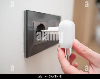 A contemporary charger is being plugged into an electrical outlet in a residential home environment Stock Photo