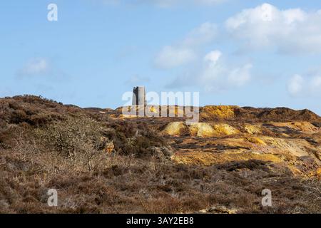 The unique and colourful open cast copper mine once the worlds largest at Parys Mountain Anglesey and windmill ruins on the summit in North Wales Stock Photo