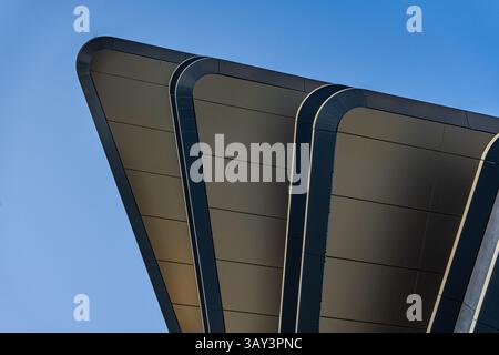 A close-up of modern architectural details showcasing sleek metallic elements against a clear blue sky, highlighting contemporary design and geometric Stock Photo