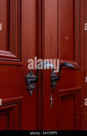 Close-up of aged red wooden doors showcasing intricate vintage iron handles, embodying the historical charm of Prague's architectural heritage and tim Stock Photo