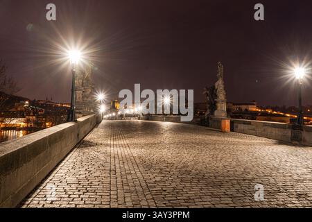 Illuminated at night, Charles Bridge in Prague showcases statues and cobblestones under glowing streetlights, reflecting Old Prague's architectural be Stock Photo