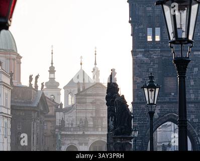 Early morning light bathes the historic statues and classic architecture of Prague in a warm glow, highlighting the blend of old European charm and he Stock Photo