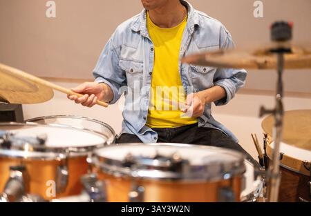 A musician energetically plays the drums in a professional recording studio. The scene captures passion and musical creativity in an acoustic setting. Stock Photo