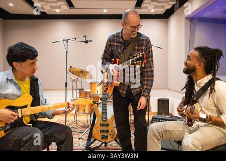 Musicians collaborate in a soundproof recording studio, surrounded by instruments and equipment. The atmosphere is creative and lively, capturing the Stock Photo