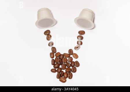 Coffee beans creatively arranged alongside two white biodegradable capsules on a plain background. The beans are scattered to mimic a fresh pour, evok Stock Photo