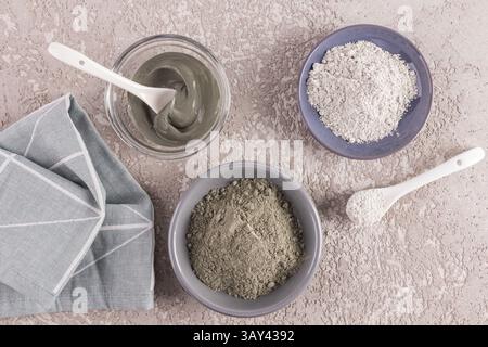 Top view of different types of cosmetic clay and a prepared clay facial mask arranged in bowls on a textured surface, showcasing natural skincare ingr Stock Photo