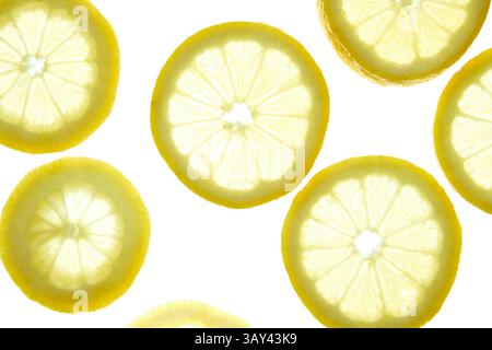 Slices of lemon arranged on a light background, showcasing their vibrant yellow color and detailed texture. The citrus pattern creates a refreshing an Stock Photo