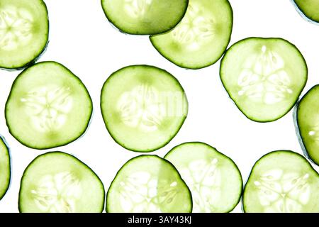 Slices of fresh cucumber are arranged on a light background, showcasing their crisp texture and vibrant green color. Ideal for healthy eating or skinc Stock Photo