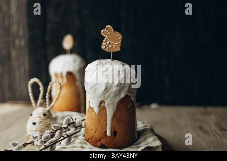 Traditional Russian kulich bread topped with white glaze and cute Easter-themed decorations, presented on a rustic wooden table for a festive celebrat Stock Photo