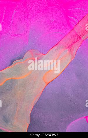 Vivid neon pink, orange, and purple hues swirl dynamically over a matte black paper backdrop, creating a mesmerizing and electrifying abstract pattern Stock Photo