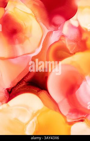Vibrant liquid abstract inks flow together, featuring a mesmerizing mix of deep red, bright orange, and warm yellow. Stock Photo