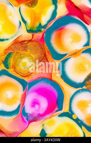 An abstract image featuring vibrant swirls of ink in a variety of colors including pink, yellow, orange, blue, and green on a glossy background. The m Stock Photo