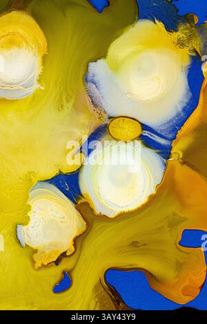 A swirling abstract design featuring vibrant shades of blue and yellow, merging with subtle hints of white and gold in an ethereal ink flow on a smoot Stock Photo