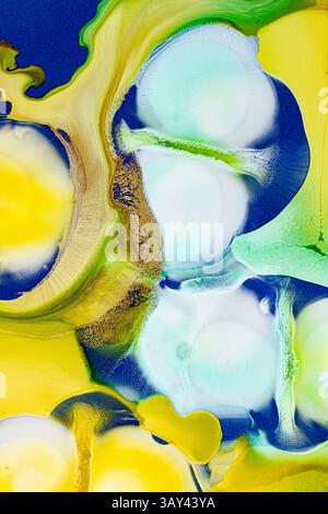 This image features dynamic flows of abstract ink in vibrant colors like blue, green, yellow, and hints of gold on a textured background, evoking a se Stock Photo