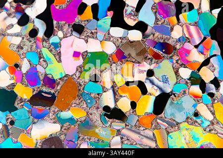 Liquid crystals under a microscope, featuring a vivid array of colors including blue, pink, orange, and green. The varied shapes and intense color var Stock Photo