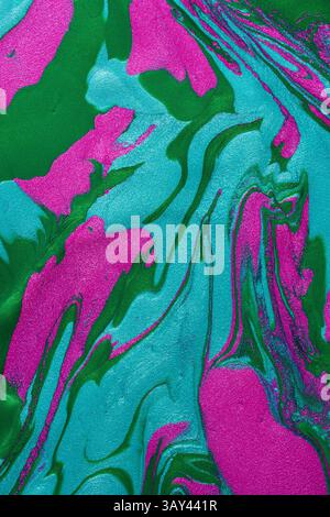 A close-up image of vibrant pink and green metallic paints swirled together, creating a dynamic and textured abstract background. Stock Photo