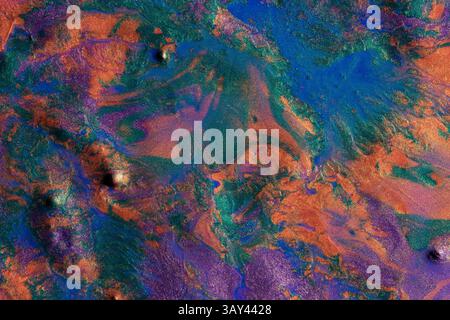 Vibrant metallic paints blend together in a chaotic yet mesmerizing pattern on this abstract background. The image captures a vivid display of blue, o Stock Photo