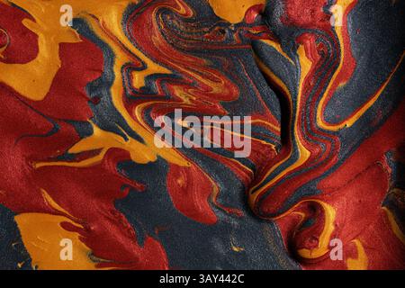 Vibrant swirls of metallic red, gold, and black paints merge, forming a captivating abstract background ideal for artistic and luxury design uses. Stock Photo