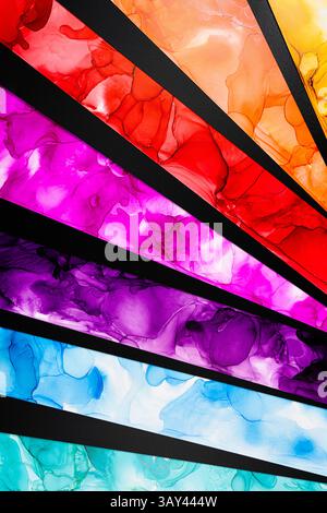 Diagonal layers of colorful ink create a dynamic abstract composition in paper. Vivid reds, purples, blues, and greens contrast with a sleek black bac Stock Photo