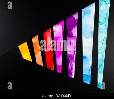 A vibrant geometric pattern with colorful segments on a black background of paper. Each segment features bright hues such as yellow, red, pink, and bl Stock Photo
