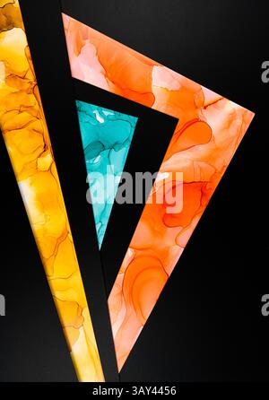 A vibrant abstract design featuring triangular shapes with fluid ink patterns in orange, yellow, and teal, contrasted against a black background on pa Stock Photo