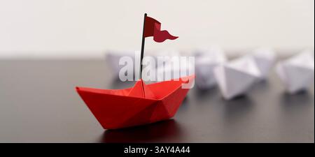 Red origami boat with a small flag positioned on the right against a clean white background, showcasing a minimalist design and bright colors. Stock Photo