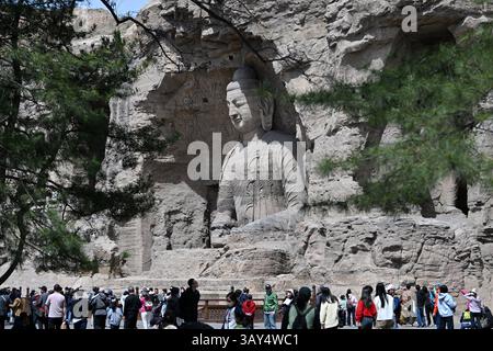 (250422) -- DATONG, April 22, 2025 (Xinhua) -- Tourists visit Yungang Grottoes in Datong, north China's Shanxi Province, April 16, 2025. Yungang Grottoes was built during the Northern Wei Dynasty (386-534). It is considered a pinnacle of Chinese Buddhist art and represents the highest level of sculptural artistry in the world during the 5th century.  In recent years, Shanxi has made great efforts to protect and study the grottoes. In 2021, the research institute of the Yungang Grottoes was established for the protection, research and management of the Yungang Grottoes.    Since 2003, the UNESC Stock Photo