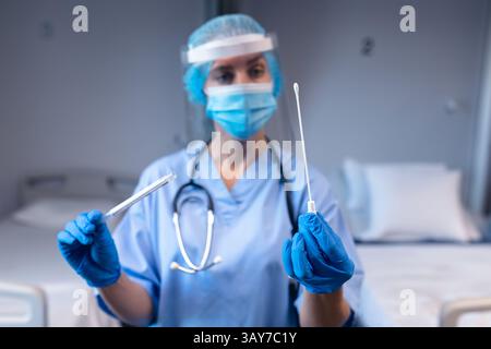 Female healthcare worker holding sterile swab, sample tube in hospital lab with stethoscope Stock Photo