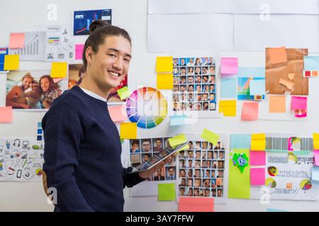 Asian man standing in creative studio, reviewing ideas on tablet with color wheel chart, copy space Stock Photo