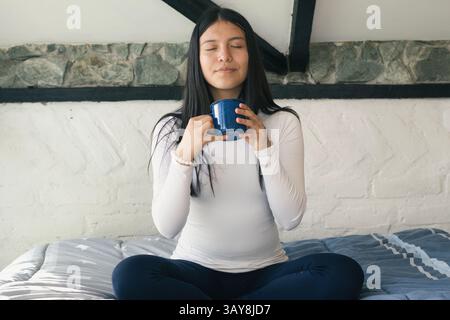 A young woman enjoys a peaceful moment sipping warm coffee, embodying true relaxation and tranquility Stock Photo
