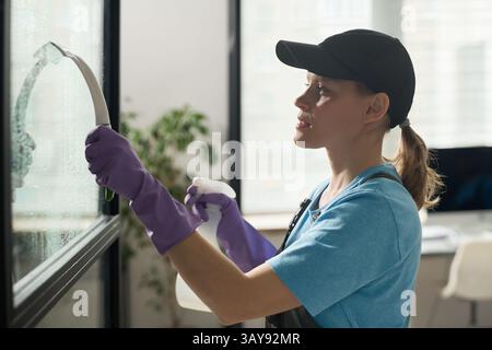 Woman Washing Windows In Office Stock Photo