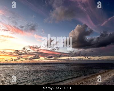 Breathtaking sunset over the ocean, where vibrant colors dance across the sky, reflecting on the tranquil waters below. The dramatic clouds add depth Stock Photo