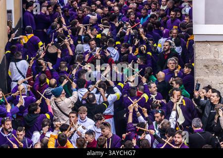 Turbas de Cuenca in purple robes make a deafening noise with their drums (tambores) and trumpets (clarines) at the head of the Camino del Calvario procession, which passes through Cuenca on Good Friday. Plaza Mayor, Cuenca, Castilla-La Mancha, Spain Stock Photo