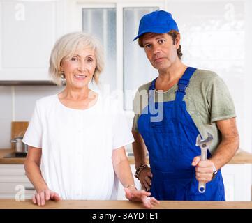 Plumber and woman homeowner posing in kitchen Stock Photo