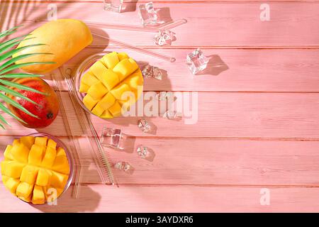 Summer party concept. Fresh red and light mango fruits and its slices with cocktail sticks and ice cubes, bar and leisure concept, restaurant and cafe Stock Photo