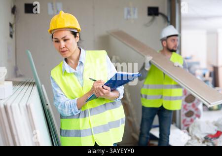 Female building inspector taking inventory of materials at construction site Stock Photo