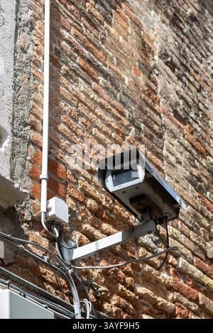 Old Surveillance Camera on Brick Wall with Cables Stock Photo