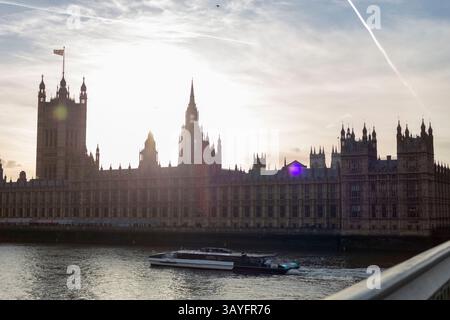 Palace of Westminster and Uber Boat on the River Thames at Sunset in London Stock Photo